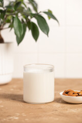 Organic almond milk in glass near the bowl with raw almonds on the table in the kitchen ready for cooking