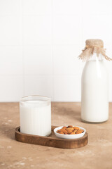 Organic almond milk in glass near the bowl with raw almonds on the table in the kitchen ready for cooking