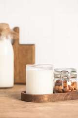 Organic almond milk in glass near the bowl with raw almonds on the table in the kitchen ready for cooking