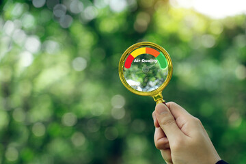 Hand holding a magnifying glass to check the good air quality and clean outdoor air quality safe. - obrazy, fototapety, plakaty