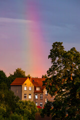 the extreme arc of the rainbow touching an old building surrounded by trees
