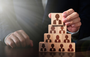 Business manager selecting leader and building successful team. Businessman stacking wooden blocks. People icons and lens flare light.