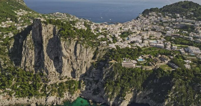 Capri Italy Aerial v5 cinematic drone flyover the sea capturing rugged coastal cliffs, azure landscape of island town and charming cliffside neighborhood in summer - Shot with Mavic 3 Cine - May 2023