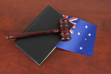 Judge gavel and legal book on wooden table with flag of Australia