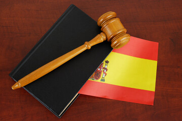 Judge gavel on legal book and flag of Spain. 