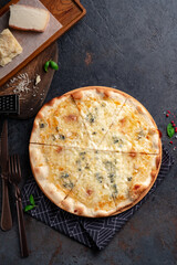 Pizza four cheeses on a dark background. Pizza 4 cheeses with gorgonzola, cheddar, mozzarella and parmesan. Top view