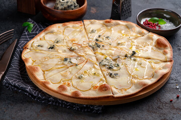 Pizza with pear and gorgonzola cheese and honey on a dark background. Close up