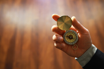 man in suit holding golden compass on gray background - obrazy, fototapety, plakaty