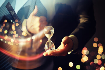 Close up of a businessman holding hourglass. Office. Morning cityscape. Concept of time management....