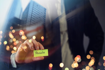 Charitable donation in business concept. Businessman shows a paper with the word donate. Double...