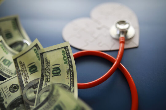A stethoscope on money and a puzzle heart. Health insurance. Healthcare and medicine. How much is the treatment. Money and medicine. World Heart Day. World Health Day.