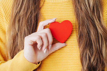 Love background. Red heart shape. Woman holding wooden heart. Young girl with heart in her fingers....