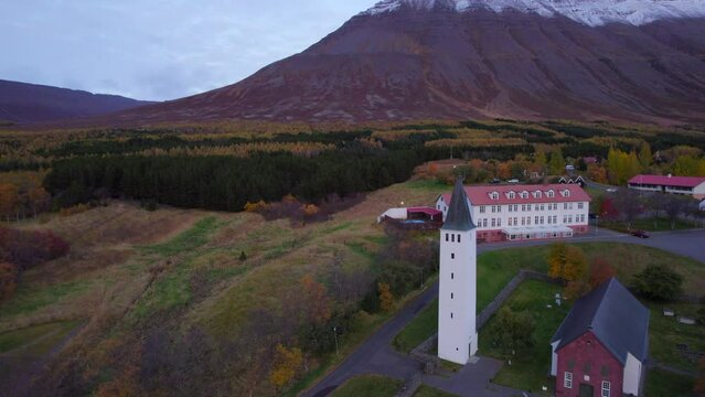 H&oacute;lar church and village in mountainous autumnal valley of north Iceland. Aerial