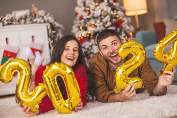 Couple holding balloons 2024 representing the upcoming New Year
