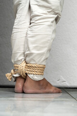 The man's legs are tied by rope
