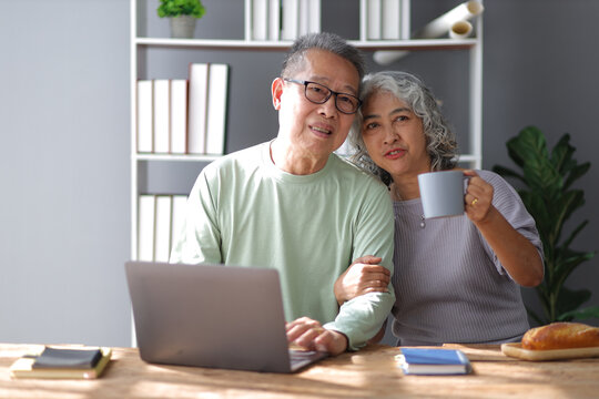 Happy senior couple in retirement at home. Men and women are using laptop in the home office.