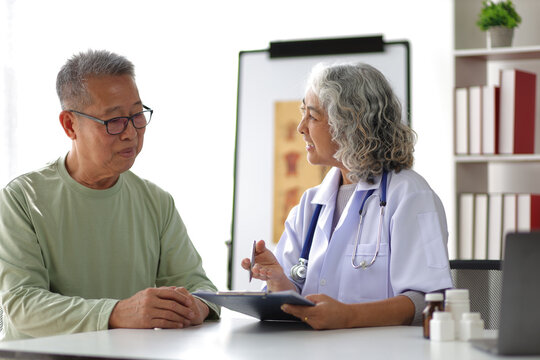 Senior health care concept. Doctor with patient in medical office. Retired man sits in a hospital examination room while discussing his health with a doctor.