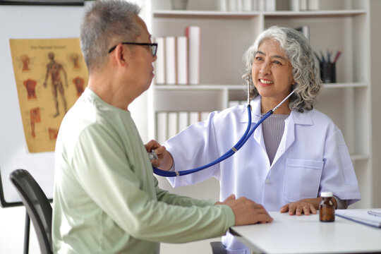 Senior health care concept. Doctor with patient in medical office. Female doctor uses a stethoscope to examine and diagnose a senior male patient.