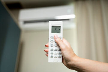 Woman's hand regulating the air conditioner with the remote control