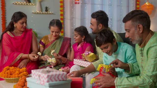 Group of Indian joint family members busy preparing gifts, lanterns and Flowers for diwali festival decoration at home - concept of holiday gathering, traditional custom and reunion