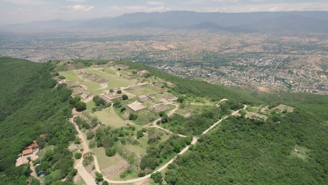 Aerial: Monte Alb&aacute;n ruins in Oaxaca, overlooking a vibrant Mexican city landscape