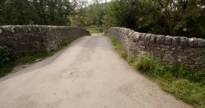 Mid shot of road going over the stone bridge at Wetton mill