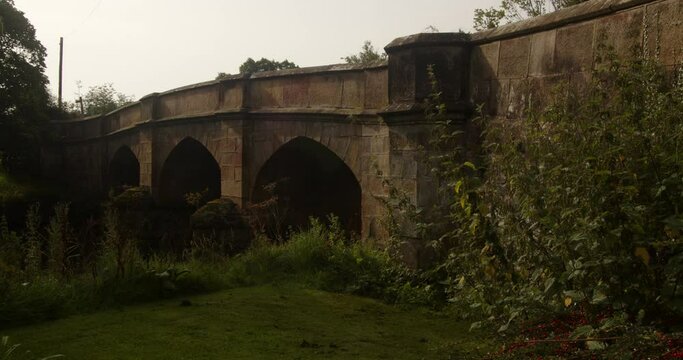 wide shot of an mediaeval stone bridge in the village of Ilam