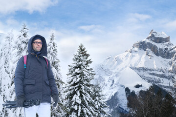 Fototapeta na wymiar young pensive man in winter clothes, guy 30 years old against backdrop of snow-capped mountains in Switzerland, concept of popular tourist destinations, beauty snowy mountain peaks and natural wonders
