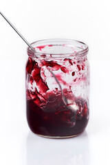 jar with delicious cherry jam half empty, white background
