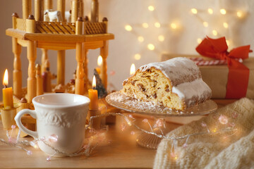 beautiful holiday composition with German Christmas cake stollen, Festive Decorations, garlands, lights, Christmas wooden carousel with candles, New Year Atmosphere, Winter Holiday Vibes