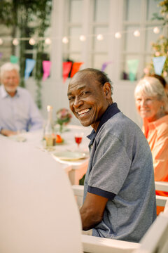 Side view portrait of smiling elderly man sitting at back yard