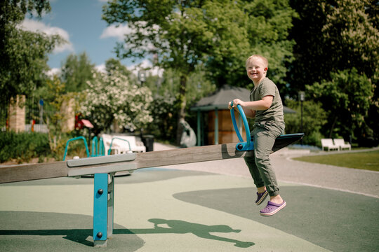 Full length side view of happy boy with down syndrome enjoying seesaw at park