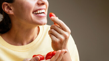 Happy young woman eating red grape tomatoes. Female eats cherry tomatoes. - Powered by Adobe
