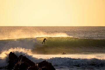 Surfer navigating a large wave in the ocean at sunset on a beautiful, clear day in Punta de Lobos