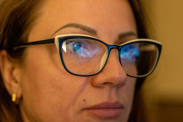 Fototapeta premium Close up shot of the woman in front of the computer screen with trading bar charts reflected in her glasses. Finance