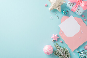 Write to Santa: A top-down view of an envelope, an empty sheet of paper, assorted baubles, a gleaming star, wintry fir branches, and wrapped gift on a soft blue surface with space for your text