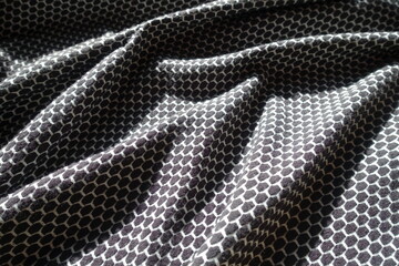 Soft folds on black and white jersey fabric with honeycomb pattern