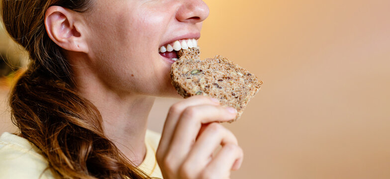 Young woman eating healthy multigrain bread close up.