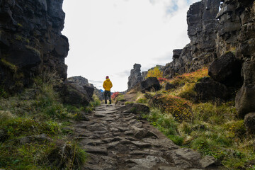 Man wearing a yellow jacket walking between the tectonic plates in the Thingvellir national park
