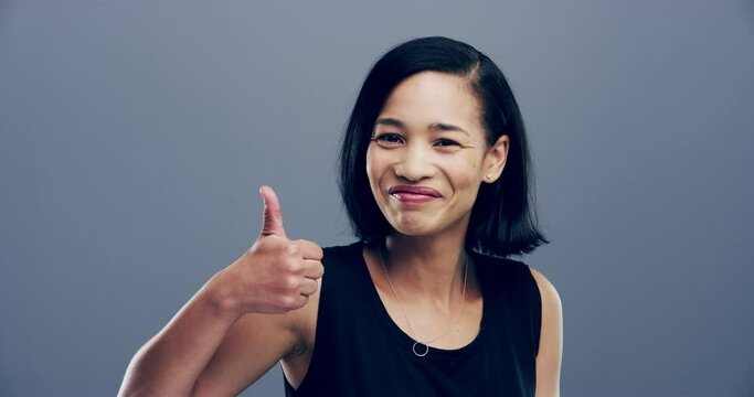 Happy woman, face and thumbs up for winning, success or good job isolated against a studio background. Portrait of excited female person smile and showing like emoji, yes sign or OK on mockup space