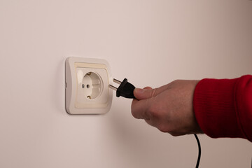 Different standards for electrical outlets. Unsuitable connector and plug in the hand of a person....