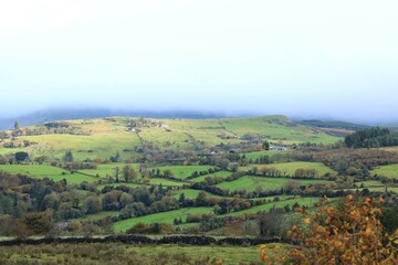 Fototapeta na wymiar Landscape at Calry, County Sligo, Ireland in autumn featuring rolling hills of farmland fields bordered by stone walls and trees against backdrop of overcast skies