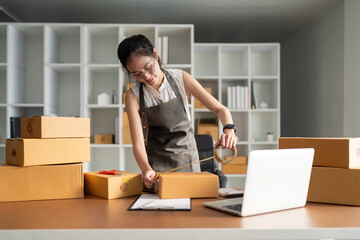 Woman asian use scotch tape to attach parcel boxes to prepare goods for the process of packaging, shipping, online sale internet marketing ecommerce concept startup business idea