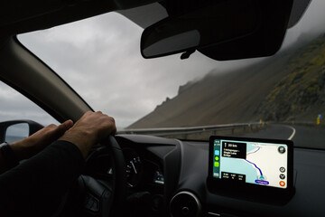 View from the car man driving using GPS in Iceland