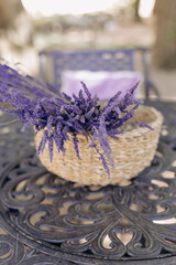 Lavender inflorescences, bright lilac, lie in wicker basket, which stands on leather table in park. 