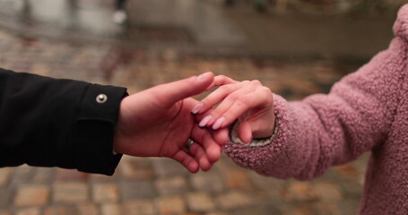 Hands of young people walking in the autumn park on a romantic date.