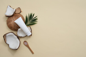 Beige background with fresh coconut and unlabeled cosmetic tube. Shower gel or lotion with Coconut extract will help retain water in the stratum corneum, leaving it feeling soft and smooth. - obrazy, fototapety, plakaty