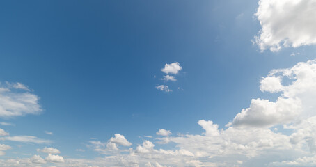 Obraz premium Panoramic view of clear blue sky and clouds, Blue sky background with tiny clouds. White fluffy clouds in the blue sky. Captivating stock photo featuring the mesmerizing beauty of the sky and clouds.