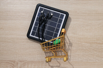 Solar panel in trolley on wooden background, top view