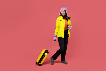 A woman in a warm ski suit with a suitcase.